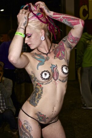 Topless woman showing off many tattoos